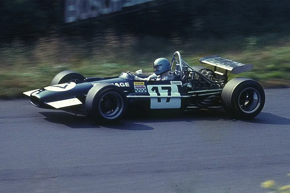 Piers Courage driving a dark blue Brabham-Ford around the Nürburgring in 1969.