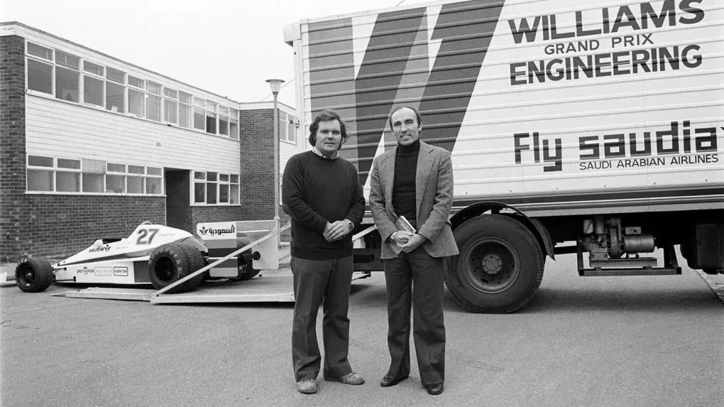 Patrick Head and Frank Williams standing outside the Didcot factory beside the FW06 and their team truck in 1978.